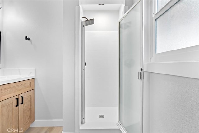 full bath featuring a stall shower, wood finished floors, vanity, and baseboards