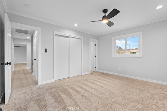 unfurnished bedroom with light carpet, a closet, and crown molding