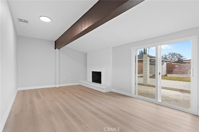 unfurnished living room featuring light wood finished floors, baseboards, visible vents, a fireplace, and beam ceiling