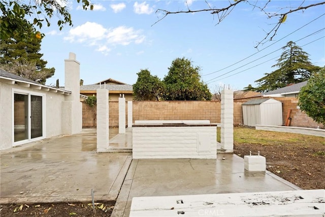 view of patio / terrace featuring an outbuilding, a fenced backyard, and a storage shed