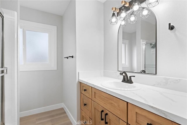 bathroom featuring a stall shower, wood finished floors, vanity, and baseboards