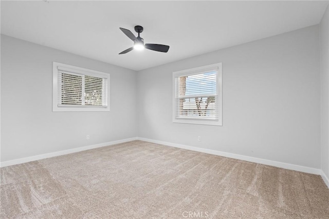 carpeted empty room featuring a ceiling fan and baseboards