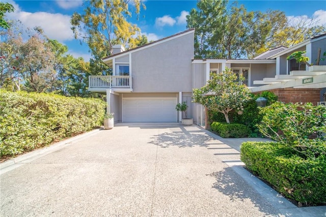 view of front of property with a garage, driveway, a balcony, and stucco siding