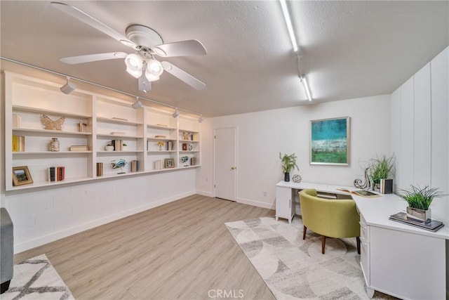 office space with a ceiling fan, baseboards, light wood-style flooring, and a textured ceiling