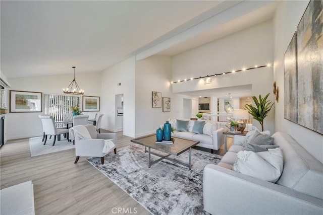 living area with a chandelier, high vaulted ceiling, baseboards, and light wood-style floors