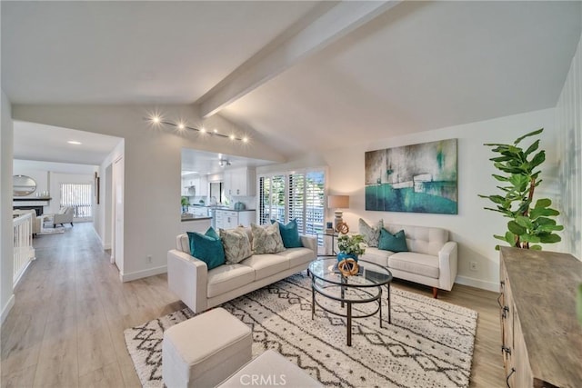 living room featuring lofted ceiling with beams, light wood-type flooring, plenty of natural light, and baseboards