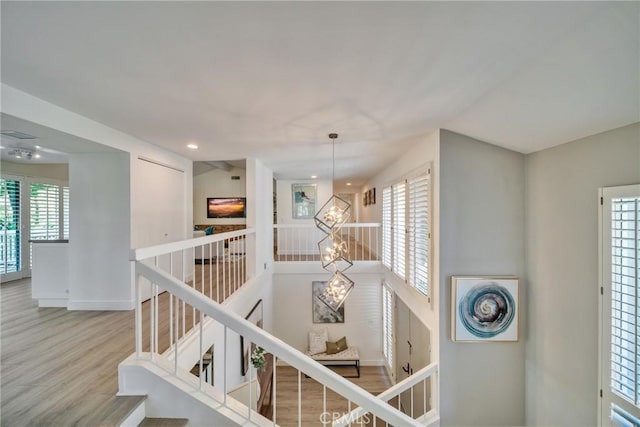 corridor featuring a wealth of natural light, baseboards, an upstairs landing, and wood finished floors