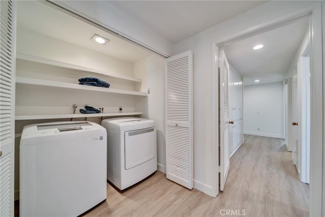 laundry room featuring washing machine and dryer, laundry area, baseboards, and light wood finished floors