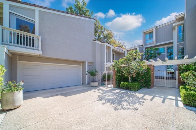 view of front of property featuring driveway, an attached garage, a gate, and stucco siding