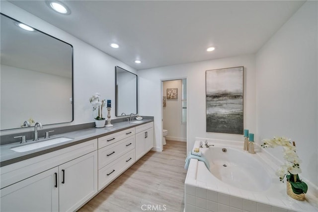 bathroom featuring wood finished floors, a sink, toilet, and a bath