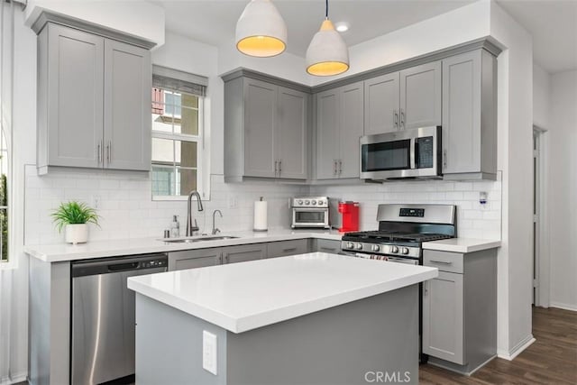 kitchen featuring dark wood finished floors, light countertops, stainless steel appliances, gray cabinetry, and a sink