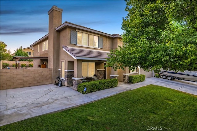 view of front of home with stone siding, a front yard, concrete driveway, and stucco siding