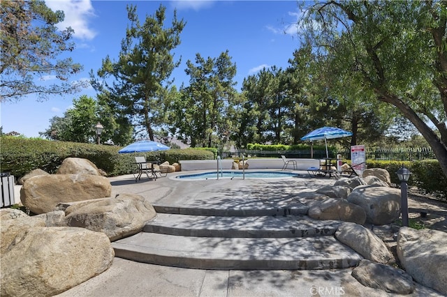 view of swimming pool featuring a patio area, fence, and a pool