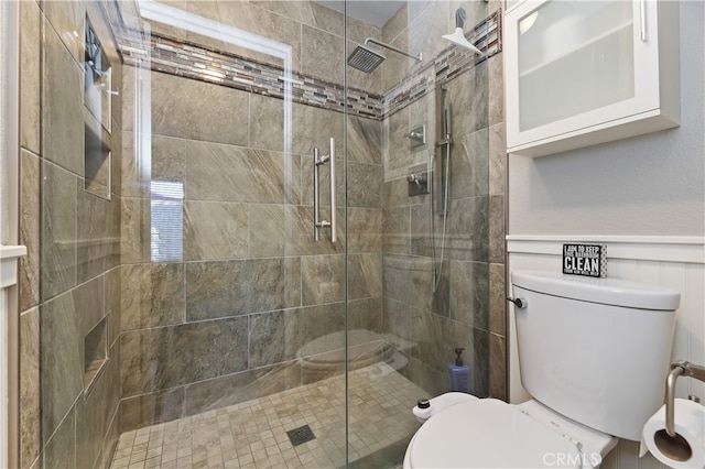 bathroom featuring a stall shower, wainscoting, and toilet