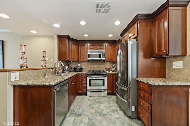 kitchen with visible vents, appliances with stainless steel finishes, light stone counters, a peninsula, and a sink