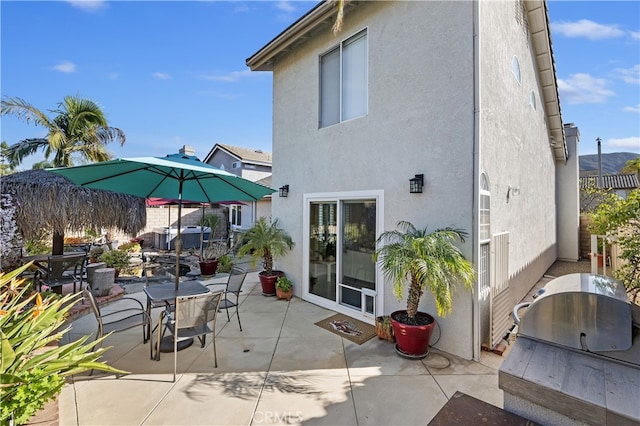 rear view of house featuring a patio area, outdoor dining area, and stucco siding