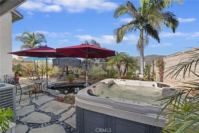 view of patio featuring cooling unit, a fenced backyard, a mountain view, and a hot tub