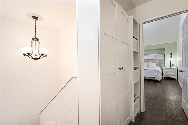 corridor featuring dark wood-style flooring and a notable chandelier