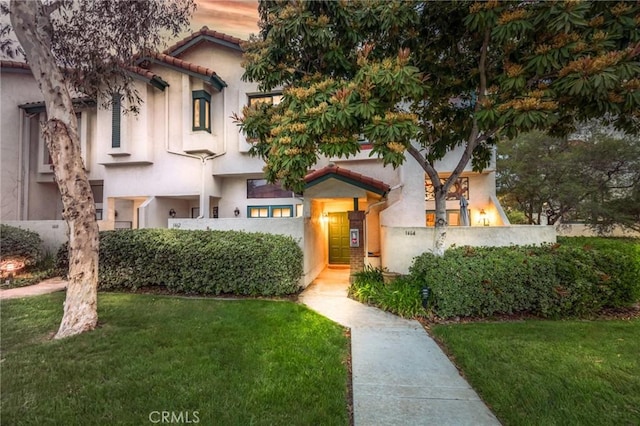 mediterranean / spanish-style home featuring a front yard, a tiled roof, and stucco siding