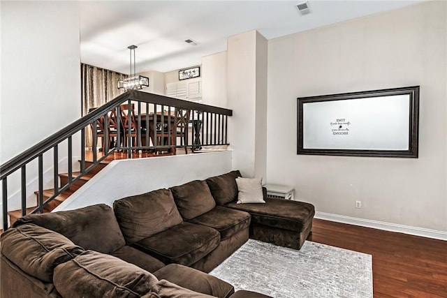 living room with a notable chandelier, wood finished floors, visible vents, and baseboards