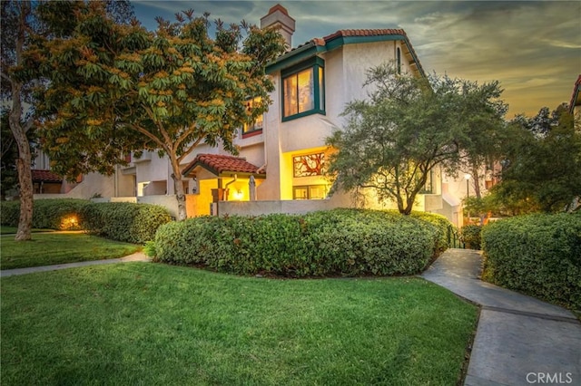 mediterranean / spanish-style home with a front yard, a tile roof, and stucco siding