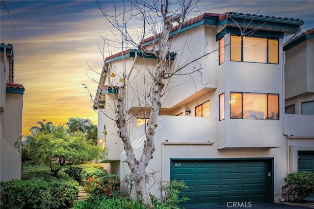 view of front of home featuring a garage, a balcony, and stucco siding