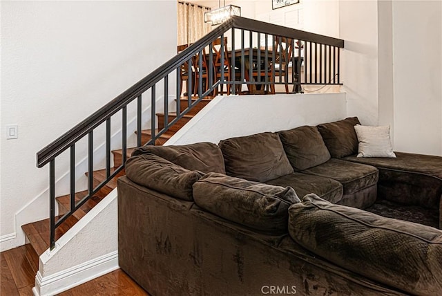 living area with stairs, baseboards, wood finished floors, and a notable chandelier