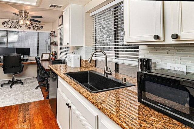 kitchen with white cabinets, black appliances, decorative backsplash, and a sink