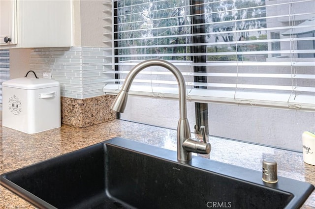 details with white cabinets, a sink, and decorative backsplash