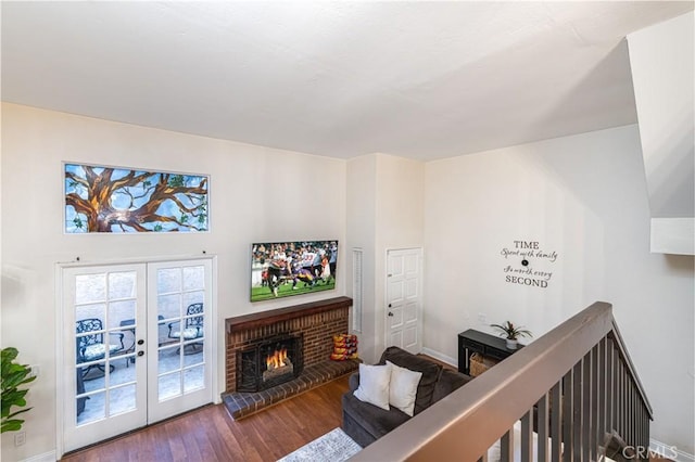 living room featuring french doors, a brick fireplace, wood finished floors, and baseboards