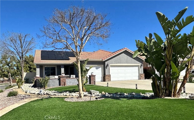 view of front of house with solar panels, a front lawn, concrete driveway, stucco siding, and an attached garage