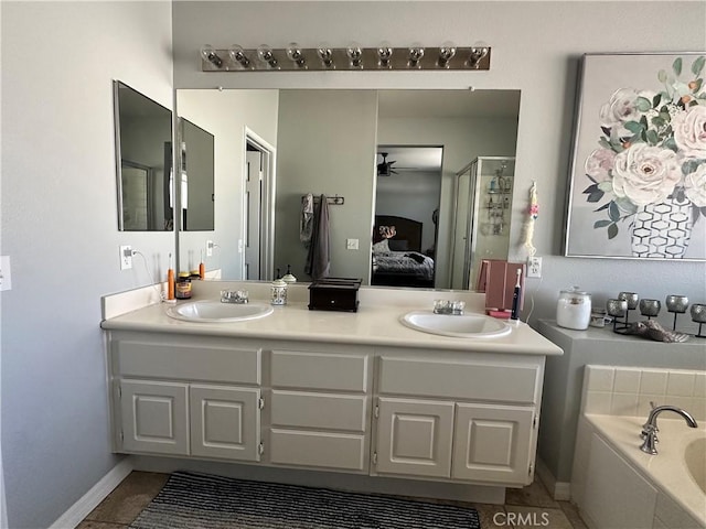 ensuite bathroom with double vanity, ensuite bath, a ceiling fan, and a sink