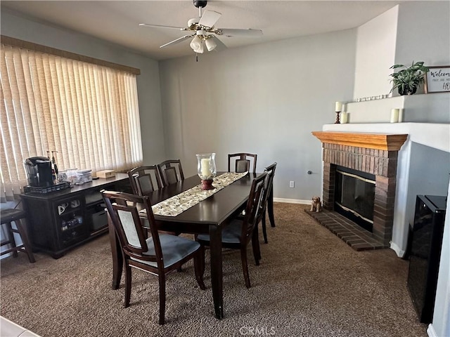 carpeted dining area with a fireplace, baseboards, and ceiling fan