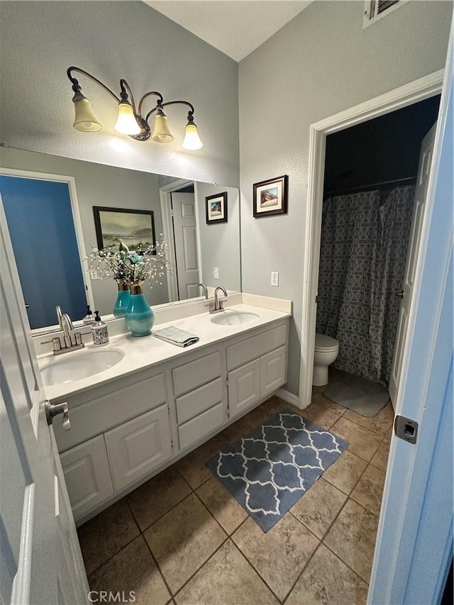 bathroom with double vanity, tile patterned floors, toilet, and a sink