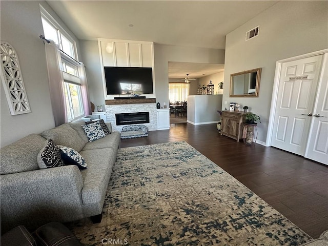 living area with visible vents, baseboards, dark wood finished floors, a chandelier, and a glass covered fireplace