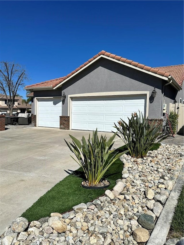 single story home with a tiled roof, stucco siding, an attached garage, and concrete driveway