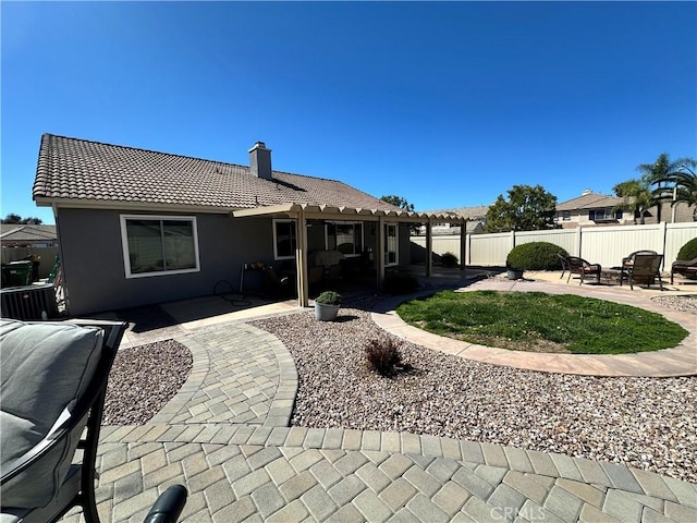 back of property featuring a patio, a tiled roof, fence, and a chimney