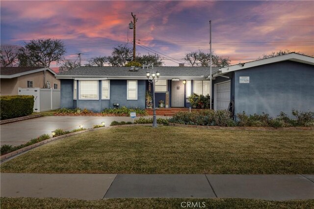 ranch-style house featuring stucco siding, a yard, and fence