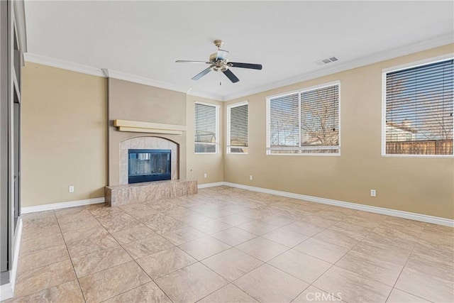 unfurnished living room with baseboards, visible vents, a ceiling fan, a tile fireplace, and ornamental molding