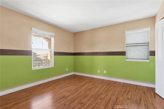 spare room featuring wood finished floors and baseboards