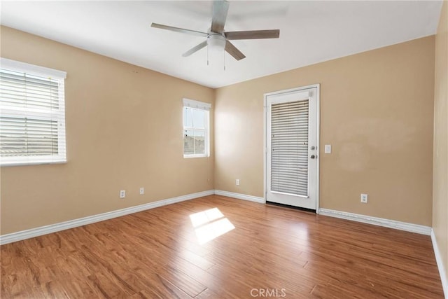 unfurnished room with wood finished floors, a ceiling fan, and baseboards