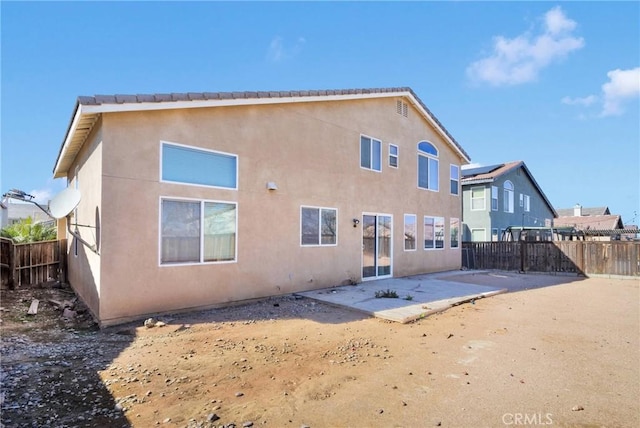 rear view of property with stucco siding, a fenced backyard, and a patio