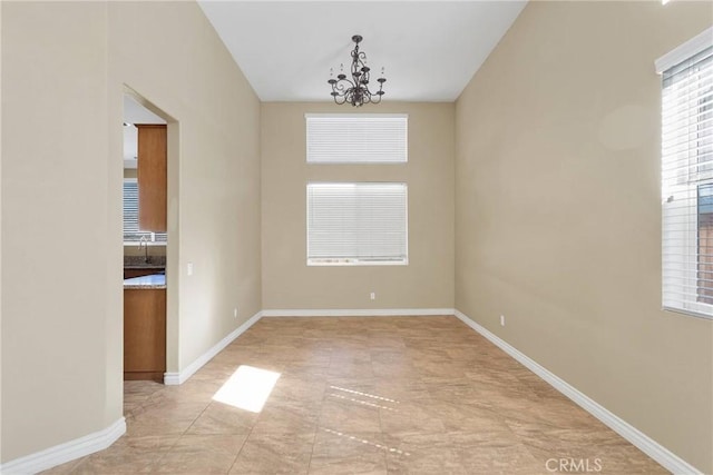 spare room featuring a chandelier and baseboards