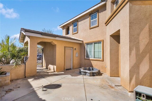 rear view of property with a patio area, a fire pit, and stucco siding