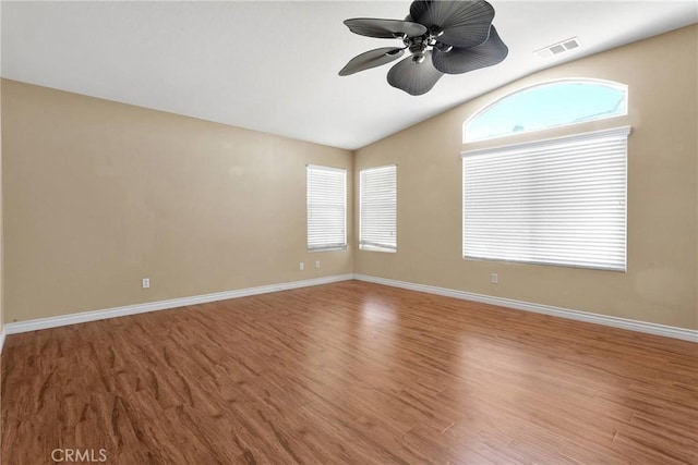 spare room featuring baseboards, visible vents, a ceiling fan, lofted ceiling, and wood finished floors