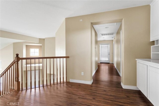 corridor with dark wood-style flooring, visible vents, and baseboards