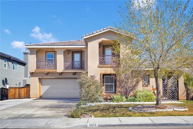 mediterranean / spanish-style house with stucco siding, an attached garage, fence, a balcony, and driveway