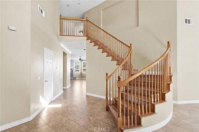 stairway featuring baseboards, visible vents, and a high ceiling