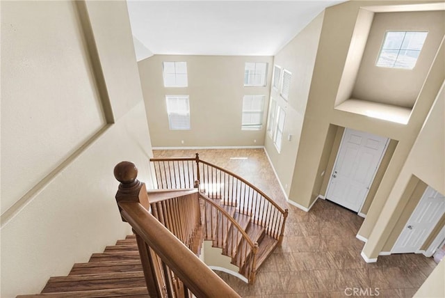 stairs featuring high vaulted ceiling and baseboards