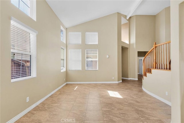 empty room featuring high vaulted ceiling, stairway, and baseboards